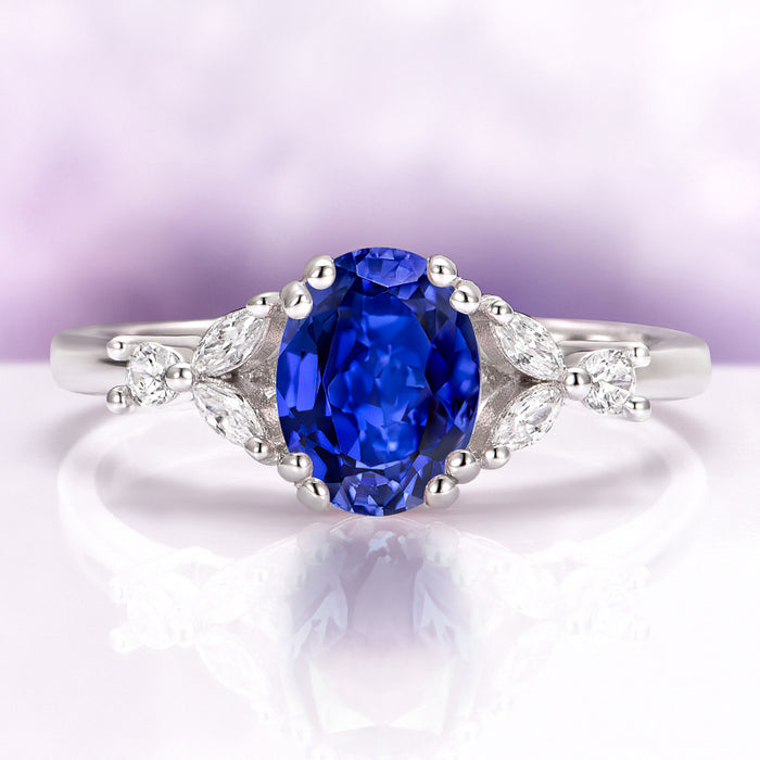 Oval Cut Blue Sapphire Engagement Ring in Sterling Silver featuring a deep blue oval sapphire accented by marquise and round diamond details on a polished band by Aquamarise.