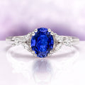 Oval Cut Blue Sapphire Engagement Ring in Sterling Silver featuring a deep blue oval sapphire accented by marquise and round diamond details on a polished band by Aquamarise.
