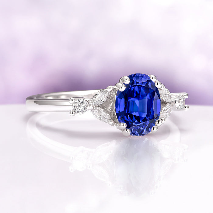 Oval Cut Blue Sapphire Engagement Ring in Sterling Silver featuring a vivid blue oval sapphire with marquise and round diamond accents on a polished band by Aquamarise.
