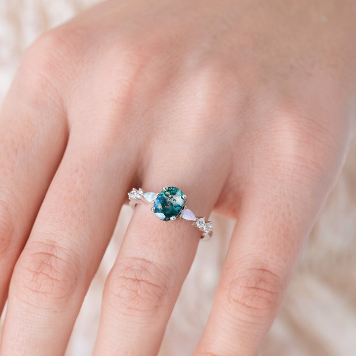 Ring with a blue gemstone on a person's finger against a neutral background