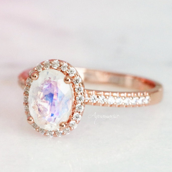 Galaxy Rainbow Moonstone Couples Ring Set featuring a luminous oval moonstone center with sparkling diamond halo and pavé diamonds on a radiant rose gold band by Aquamarise.
