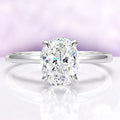 Diamond ring on a reflective surface with a light purple gradient background