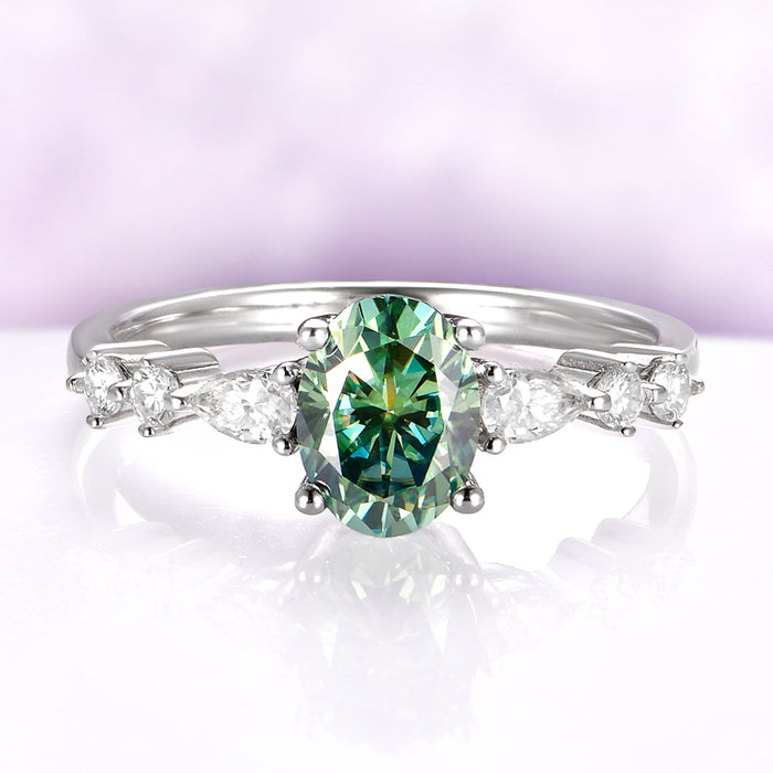Green Moissanite Engagement Ring in 14K White Gold by Aquamarise Gold, featuring an oval green moissanite centerpiece with pear-shaped and round diamond accents on a sleek white gold band.