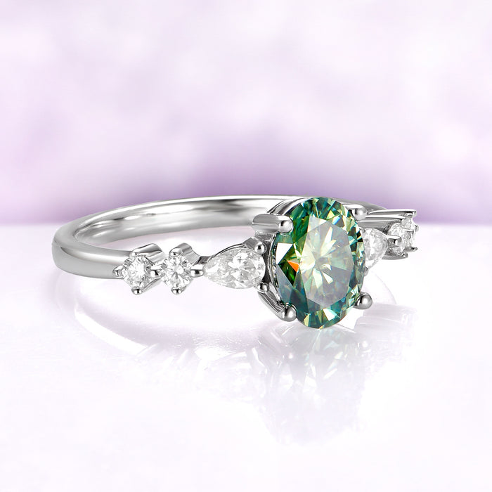 Green Moissanite Engagement Ring in 14K White Gold by Aquamarise Gold, featuring an oval green moissanite center with pear and round diamond accents on a polished white gold band.