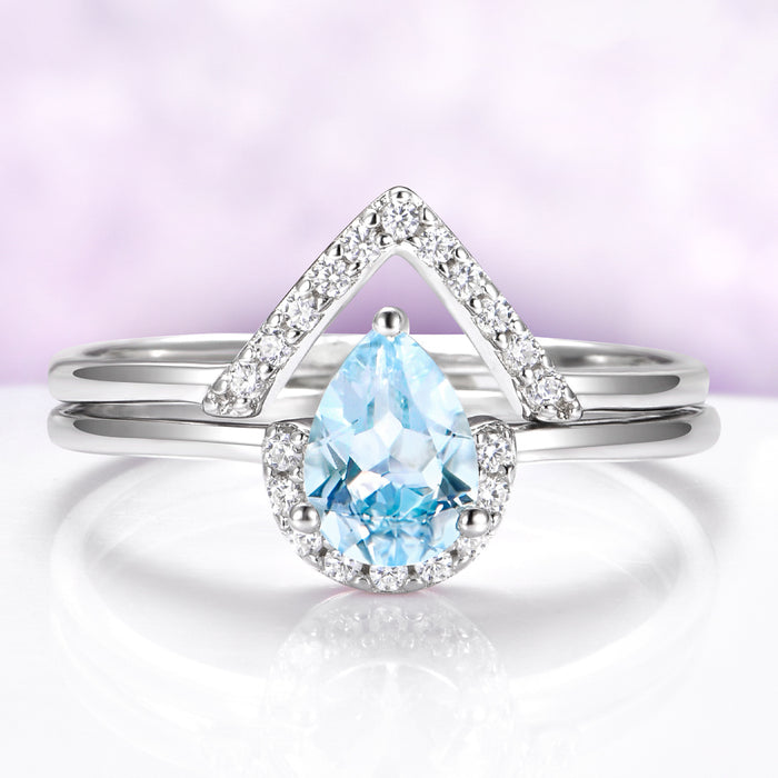 Silver ring with a blue teardrop gemstone on a light purple background