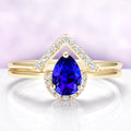 Gold ring with a blue gemstone and diamond accents on a light purple background