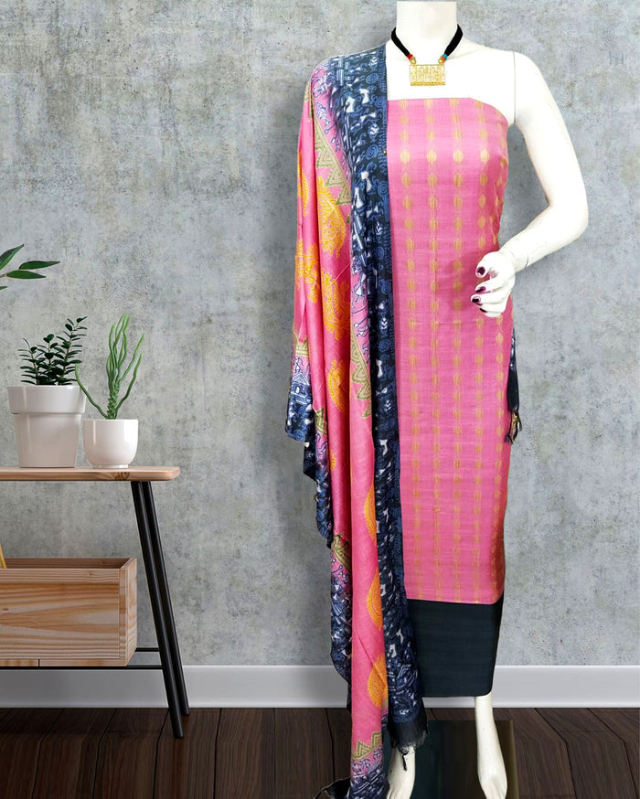 Unstitched pink Katan silk suit set with vertical rows of small geometric block print on the top and a dupatta of large black floral and geometric panels edged with decorative geometric bands.