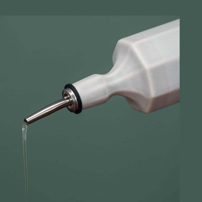 Handcrafted porcelain olive oil dispenser pouring oil with a satin-smooth glaze, perfect for kitchen use.