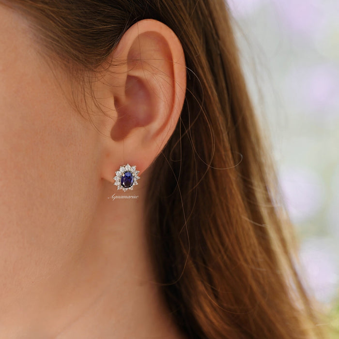 Princess Diana Blue Sapphire Stud Earrings in Sterling Silver by Aquamarise, featuring deep blue oval sapphires surrounded by sparkling simulated diamonds on a polished silver setting.
