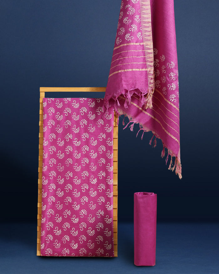 Fuchsia purple katan silk unstitched suit set with all-over white and pale gold floral hand block print, and a dupatta with striped ends and decorative fringe.