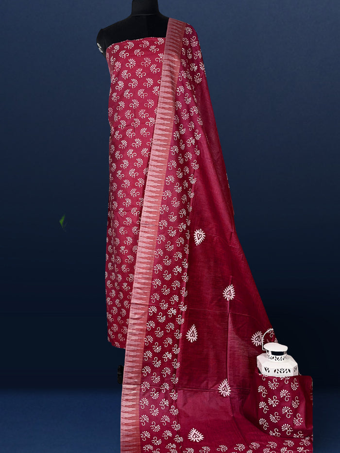 Fuchsia purple katan silk unstitched suit set with all-over white and pale gold floral hand block print, and a dupatta with striped ends and decorative fringe.