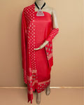 Bold red katan silk unstitched suit set with wide cream and beige block-printed borders of geometry and stylised florals at the dupatta ends.