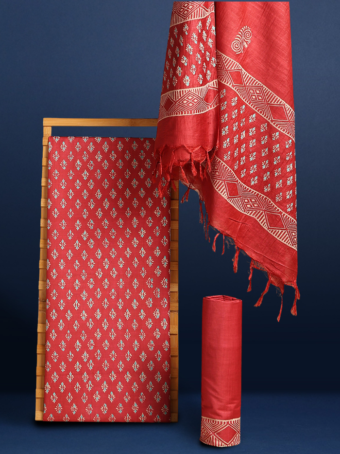 Bright red katan silk unstitched suit set hand block printed with small angular teal and off-white sprigs and geometric bands at the ends of the length.