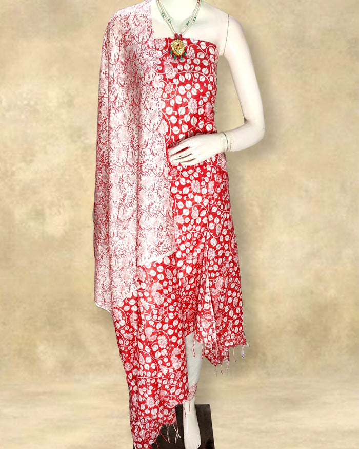 Red Katan silk unstitched suit set hand block printed with cream peacocks and floral vines in an all-over repeat, with a fringed dupatta and a horizontal patterned band on the bottom piece.