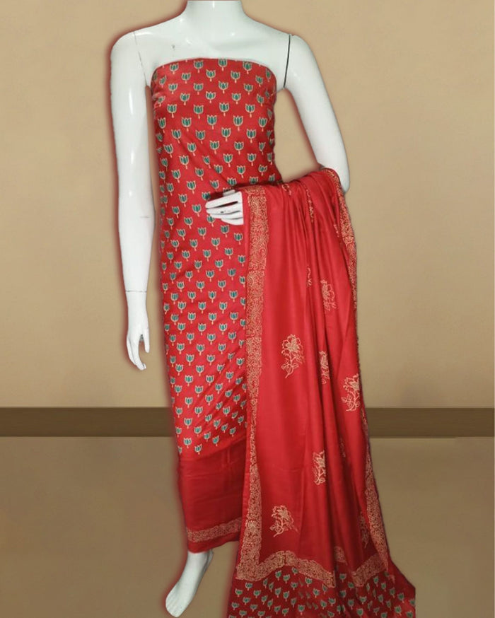 Vivid red katan silk unstitched suit set hand block printed with upright teal and pale gold tulip motifs, with a dupatta framed by an intricate floral border.
