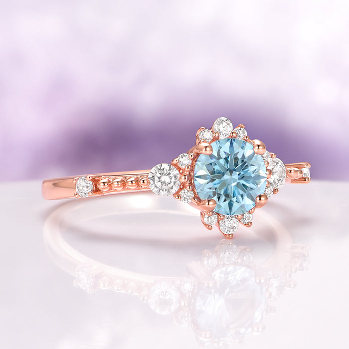 Round Cut Aquamarine Engagement Ring in 14K Solid Rose Gold featuring a radiant aquamarine center surrounded by sparkling white stones in a vintage-inspired setting by Aquamarise Gold.