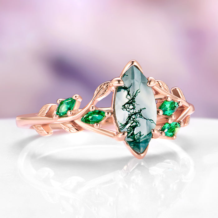 Moss Agate, Peacock Opal & Whiskey Barrel Wood Couples Ring Set featuring a marquise moss agate center stone with intricate leaf motifs and vibrant green gemstones on a rose gold band by Aquamarise.