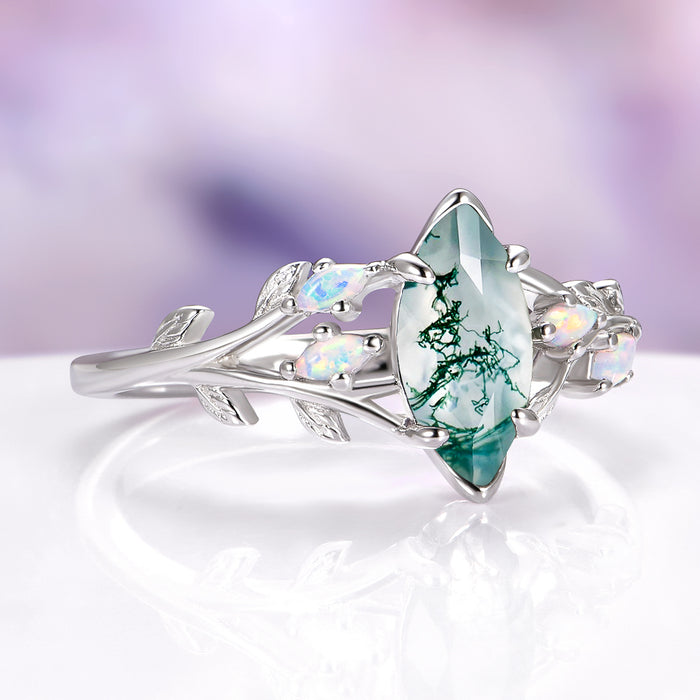 Silver ring with a green gemstone on a white surface with a blurred purple background