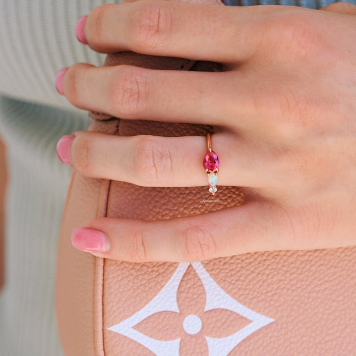Lab Grown Ruby and Natural Australian Opal Engagement Ring in 14K Solid Rose Gold by Aquamarise Gold shown on hand with pink nails holding a textured tan designer handbag.