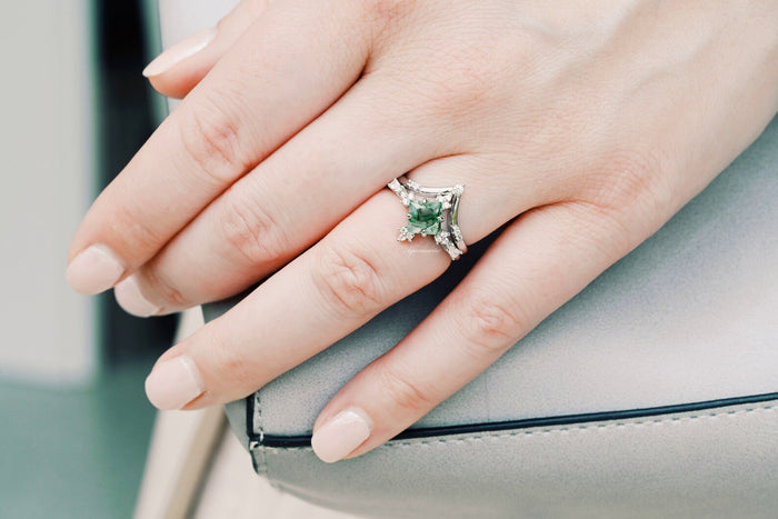 Princess Cut Moss Agate Engagement Ring Set in 14K White Gold by Aquamarise Gold, showcasing a nature-inspired green moss agate gemstone on a hand resting on a light gray purse.