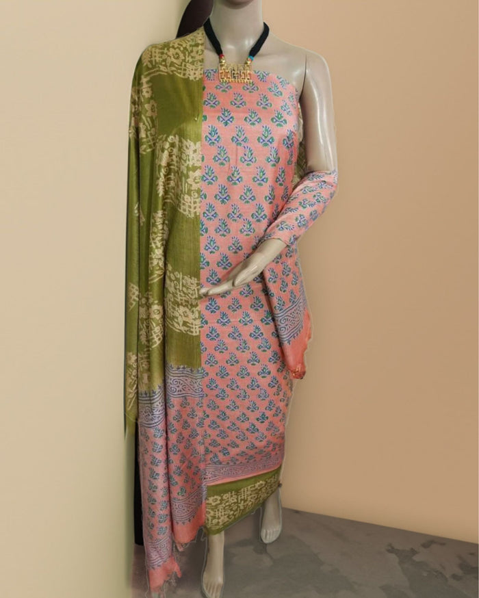 Salmon pink and olive green katan silk unstitched suit set hand block printed with small floral butas and wide geometric panels on the dupatta and bottom hem.