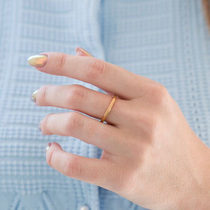 Satin Wedding Band in 14K Solid Yellow Gold (2MM) worn on a hand with iridescent nail polish, highlighting a slim, elegant matte-finish ring designed by Aquamarise Gold for everyday comfort and timeless style.