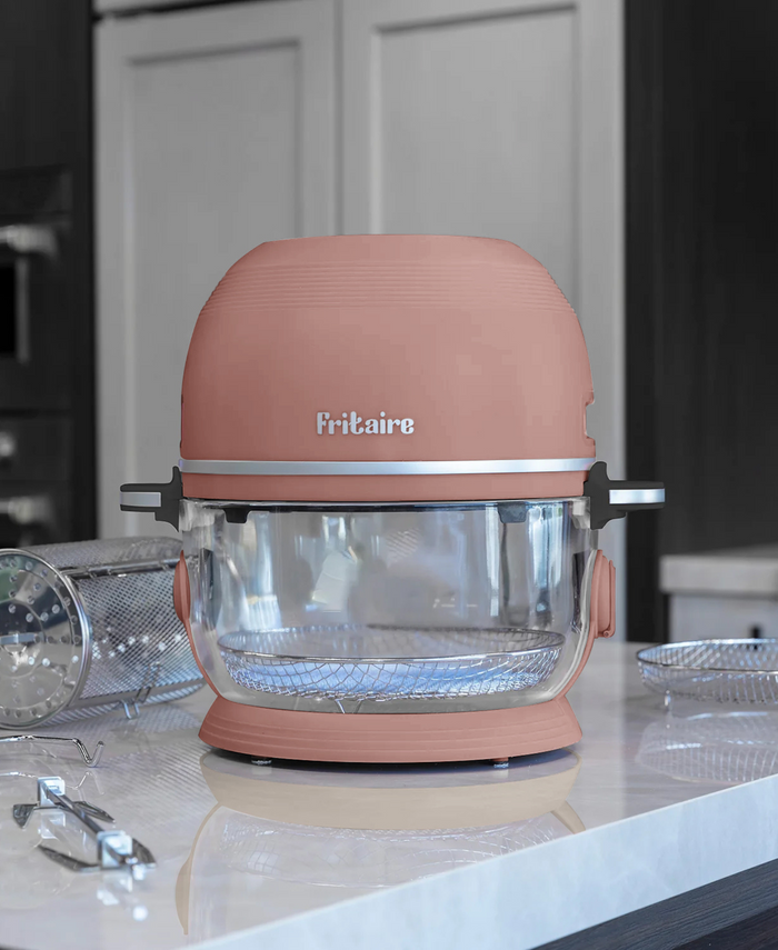 Self-cleaning air fryer in mauve rose with glass bowl on a kitchen countertop.
