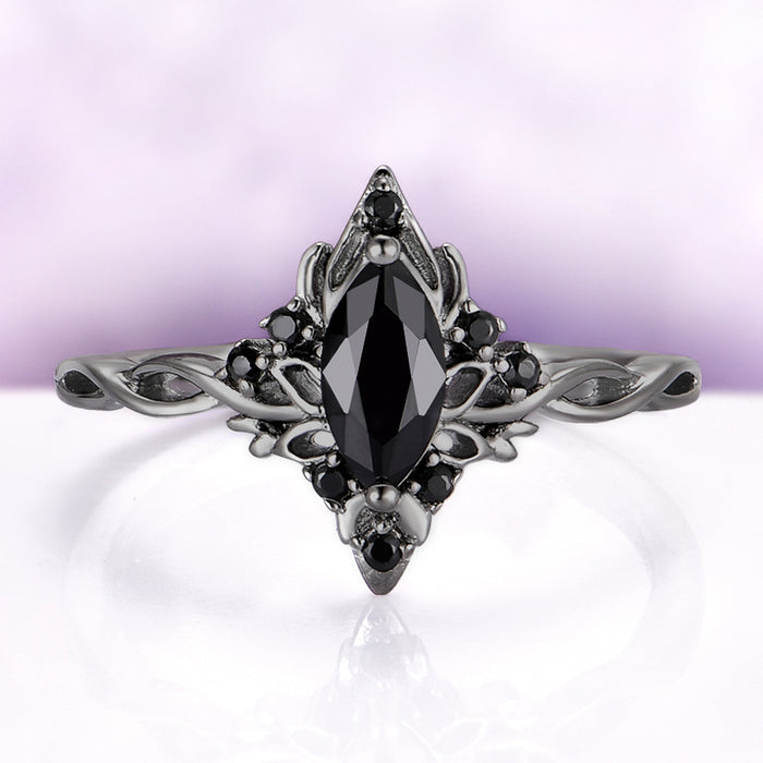 Elaborate ring with a black gemstone on a light purple background