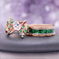 Simulated Diamond & Emerald Leaf Couples Ring Set by Aquamarise, pairing a rose gold leaf ring with a green emerald inlay band on a dark stone pedestal.