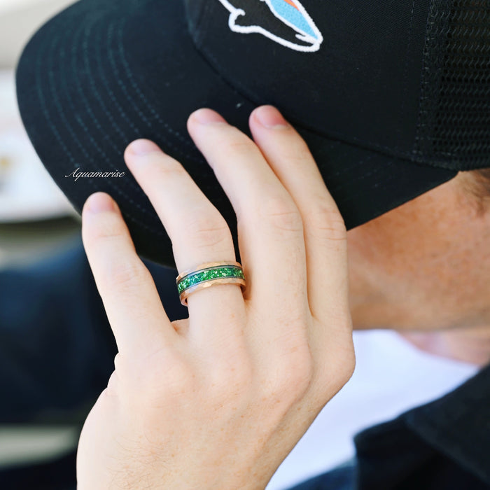 Simulated Diamond & Emerald Leaf Couples Ring Set displayed on a hand wearing a black cap, featuring a hammered rose gold band with a vibrant green emerald inlay, part of Aquamarise’s Matching Couples' Rings collection.