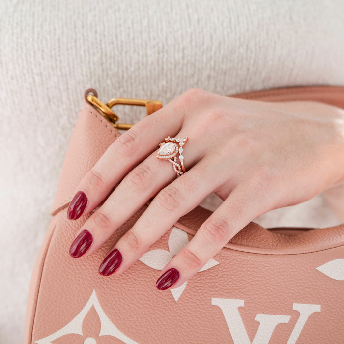 Nouveau Lab-Grown Diamond Engagement Ring- 14K Solid Rose Gold (IGI Certified) by Aquamarise Gold, featuring a pear-shaped center diamond and a twisted pavé vine band on a hand holding a pink designer handbag.