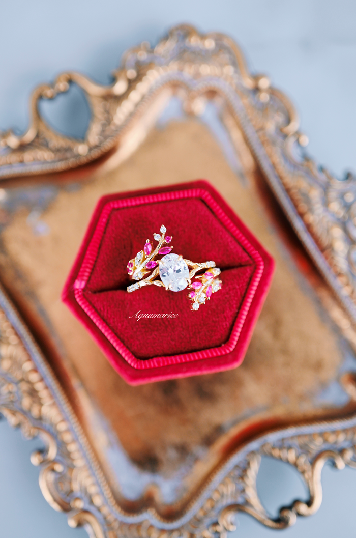 Simulated Diamond & Ruby Leaf Engagement Ring Set in 14K Yellow Gold Vermeil displayed in a red velvet hexagonal box on an ornate gold tray, featuring intricate leaf motifs and vibrant ruby accents by Aquamarise.