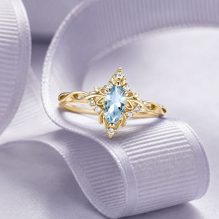 Yellow gold marquise aquamarine ring with a vintage filigree halo displayed on a white silk ribbon, Aquamarise collection banner