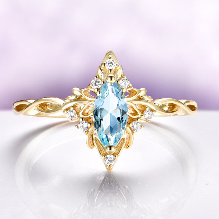 Siren Queen Marquise Aquamarine Lotus Engagement Ring in Solid 14K Yellow Gold by Aquamarise Gold, featuring a marquise aquamarine and leaf-inspired gold details with diamond accents.