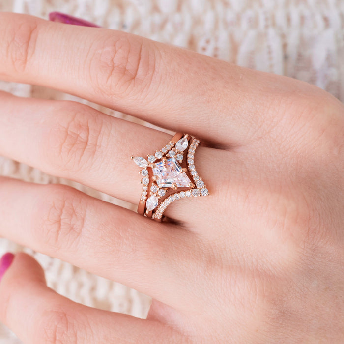 Rose gold engagement ring set with kite cut pink morganite center stone and diamond accents on hand over a light background