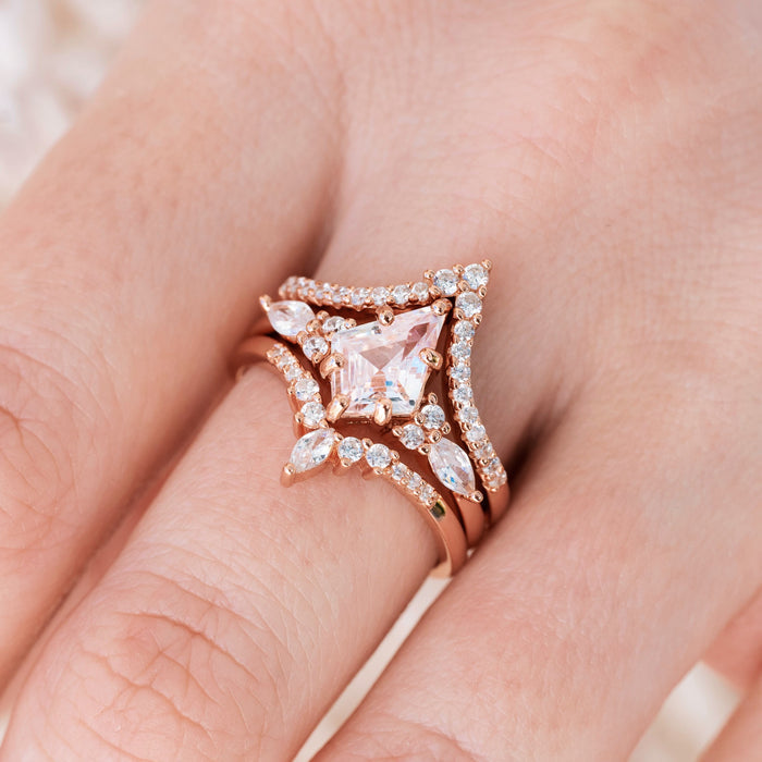 Rose gold engagement ring set with kite cut pink morganite center stone and diamond accents on hand over a light background