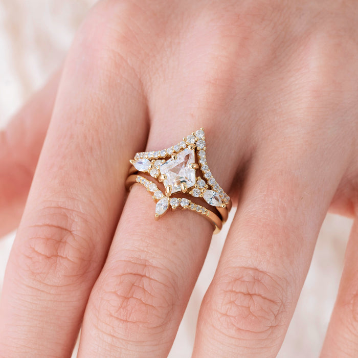 Yellow gold engagement ring set with kite cut diamond center stone and accents on hand over a light background