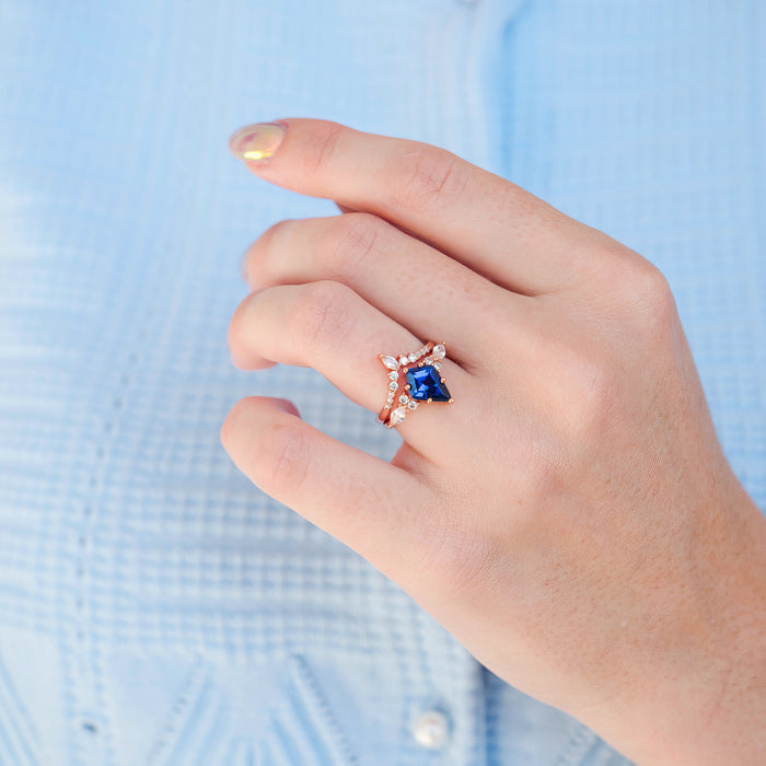 Hand wearing Skye Kite® Orion Nebula™ & Cornflower Sapphire Couples Ring Set featuring rose gold and deep blue sapphire, a celestial-inspired matching couples ring by Aquamarise.