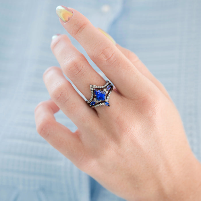 Skye Kite® Cornflower Sapphire Ring Set- Black Ruthenium worn on hand, featuring a vibrant kite-cut cornflower blue sapphire centerpiece surrounded by sparkling white gemstones on black ruthenium over sterling silver by Aquamarise, part of September Birthstone Jewelry and Fantasy-Inspired Engagement Rings collections.