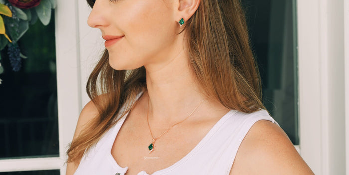 Skye Kite® Emerald Stud Earrings in 14K Rose Gold Vermeil by Aquamarise, featuring kite-cut emerald studs worn with a matching pendant necklace and casual white top.