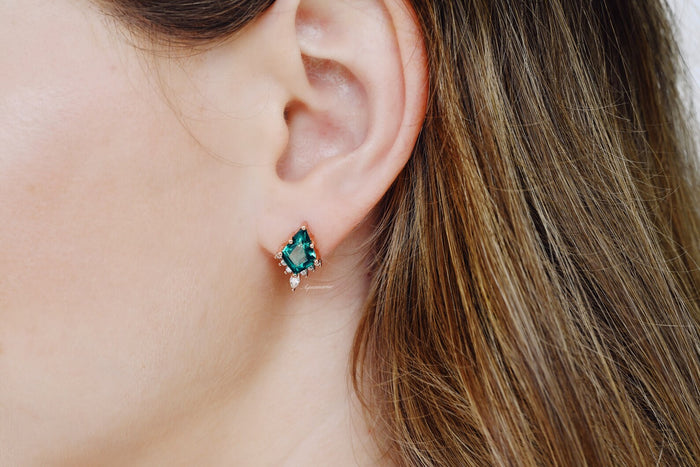 Skye Kite® Emerald Stud Earrings in 14K Rose Gold Vermeil by Aquamarise, featuring kite-cut emeralds accented with small white stones on a woman's ear.