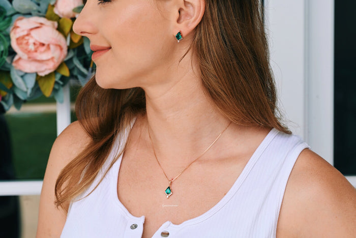 Skye Kite® Emerald Stud Earrings in 14K Rose Gold Vermeil by Aquamarise, featuring kite-cut emeralds worn with a matching pendant necklace on a woman in a white top.