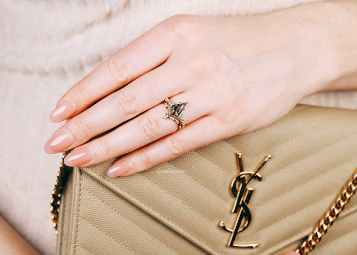 Skye Kite® Galaxy Herkimer Diamond & Meteorite Couples Ring Set by Aquamarise, featuring a gold ring with black meteorite and Herkimer diamond on a hand holding a beige designer purse.