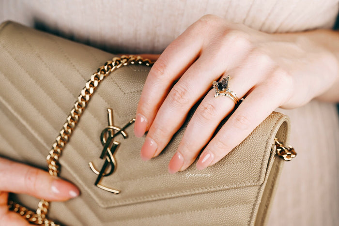 Skye Kite® Galaxy Herkimer Diamond & Meteorite Couples Ring Set by Aquamarise, featuring a unique Herkimer diamond and meteorite ring on a delicate hand holding a beige designer purse.