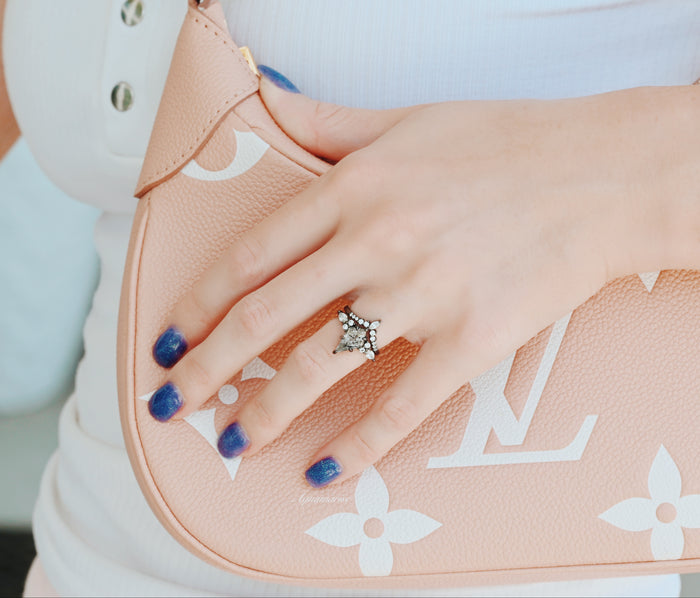 Skye Kite® Galaxy Herkimer Diamond Ring Set in Black Ruthenium on hand with navy blue nails holding a beige designer bag, showcasing Aquamarise’s unique cosmic-inspired black finish ring.