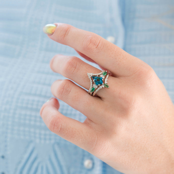 Hand wearing a star-shaped gemstone ring with a blue stone against a light blue background