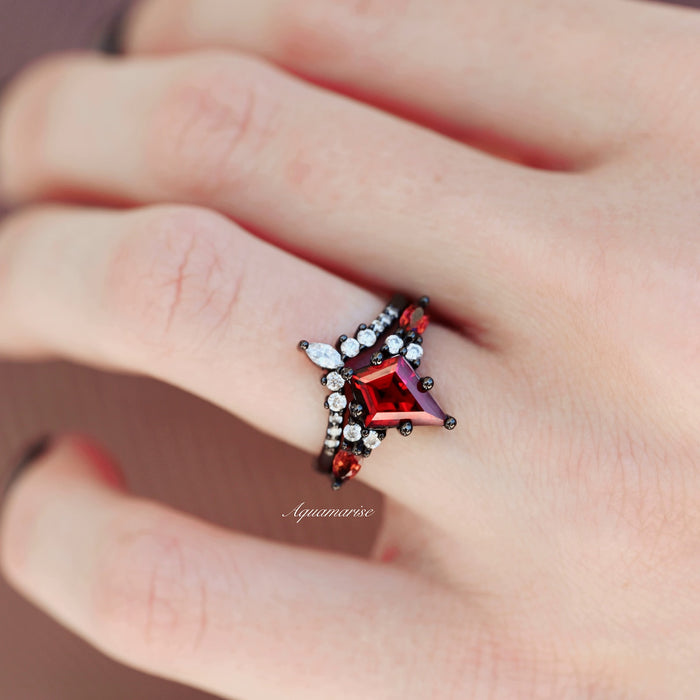 Skye Kite® Natural Red Garnet Couples Ring Set by Aquamarise showcasing a unique red garnet center with pear and round white stones on a black-finish band, a striking matching couple's ring.