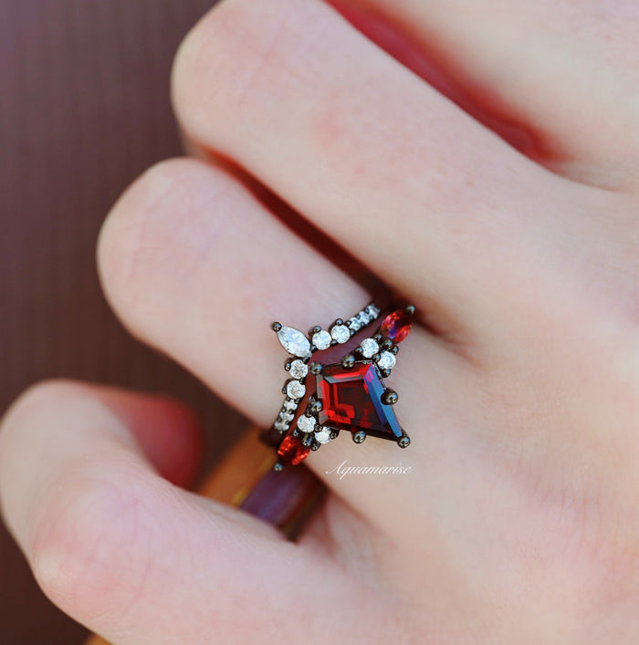 Skye Kite® Natural Red Garnet Couples Ring Set by Aquamarise featuring a unique deep red garnet centerpiece with sparkling white accent stones in a dark metal band.