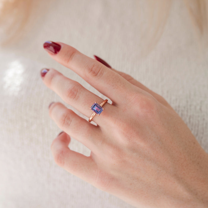 Alexandrite Engagement Ring Set- 14K Rose Gold Vermeil by Aquamarise, showing a minimalist emerald-cut color-changing alexandrite on a polished rose gold band worn on a hand.