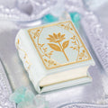Spring Court Handmade Leather Book Ring Box- Bloomlight Green Edition (Small) by Aquamarise, a delicate white leather ring box with gold floral design on an elegant silver tray.